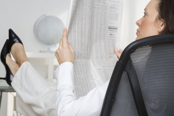 Woman reading newspaper business page.