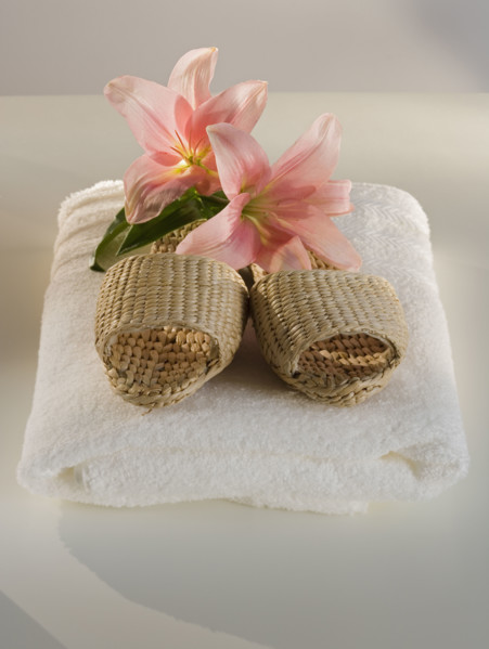 Straw sandals and flowers on folded towel.
