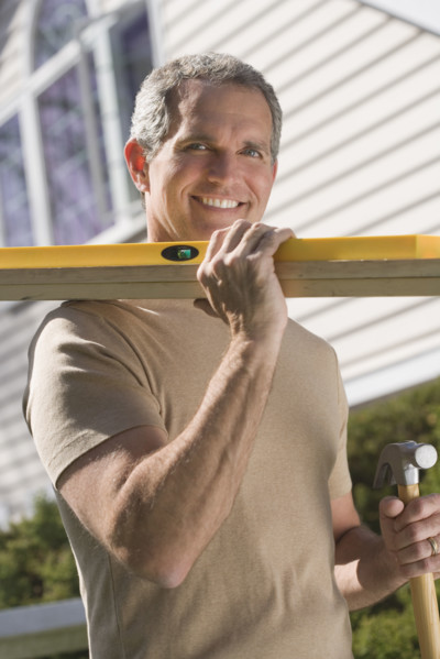 Man holding tools and wood outdoors.