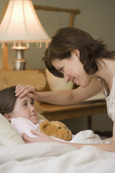 Mother checking young daughter’s temperature.