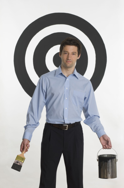 Man painting bull’s eye on wall.