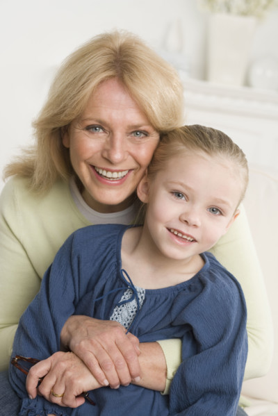 Grandmother and young granddaughter hugging sofa.