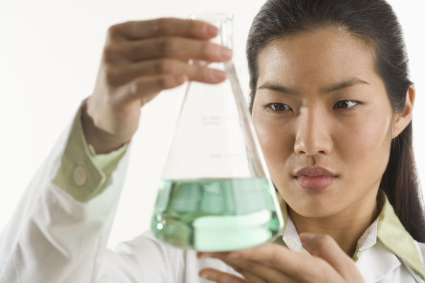 Scientist looking at glass beaker.