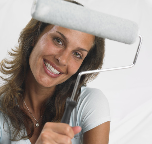 Woman smiling and holding paint roller.