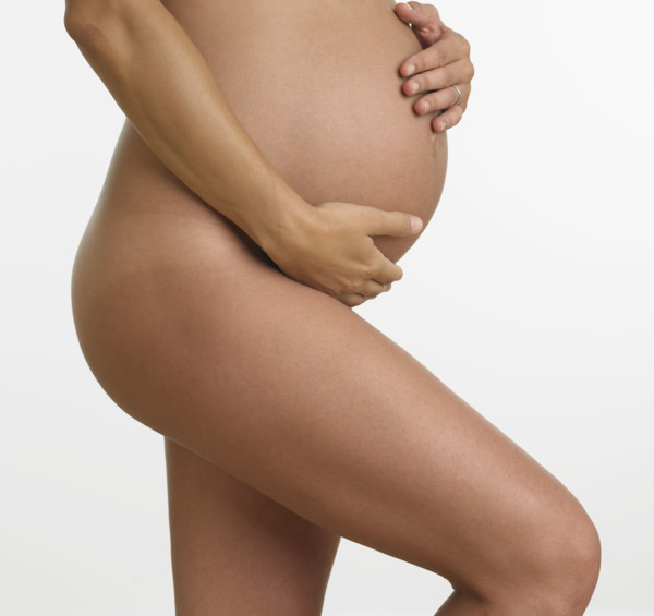 Studio shot of nude pregnant woman holding stomach.
