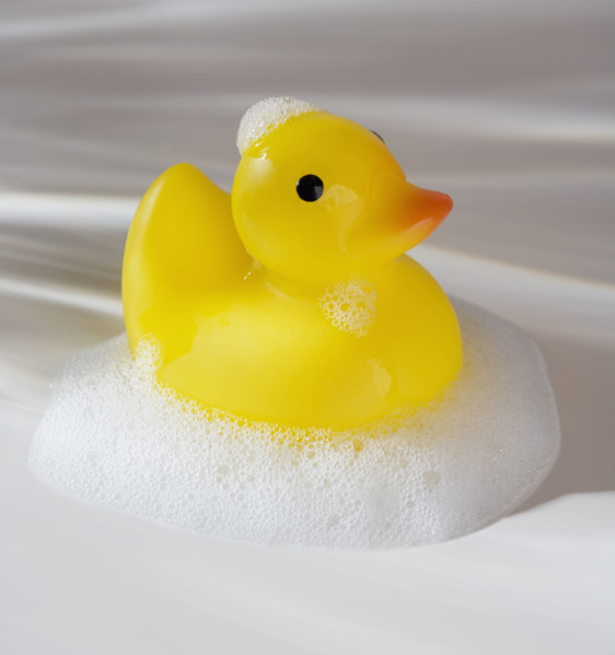 Close up of rubber duck toy with soap bubbles.