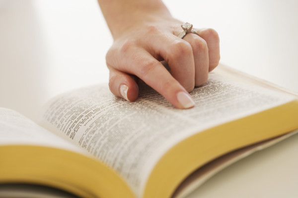 Woman's finger on page in Bible.