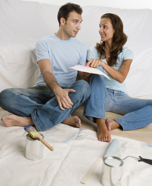 Couple sitting on tarp looking at paint swatches.