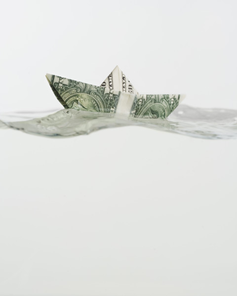 Boat made of US dollar floating on water.