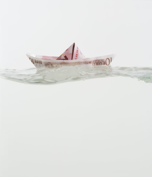 Boat made of paper money floating on water.
