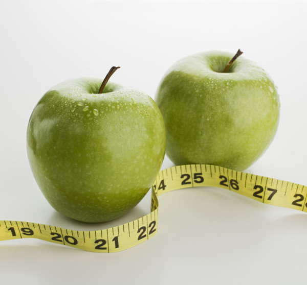 Studio shot of apples and tape measure.