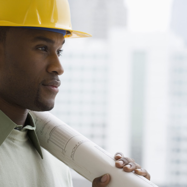 Man in hard hat holding blueprints.