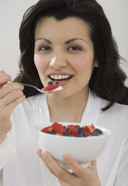 Woman eating bowl of fruit.