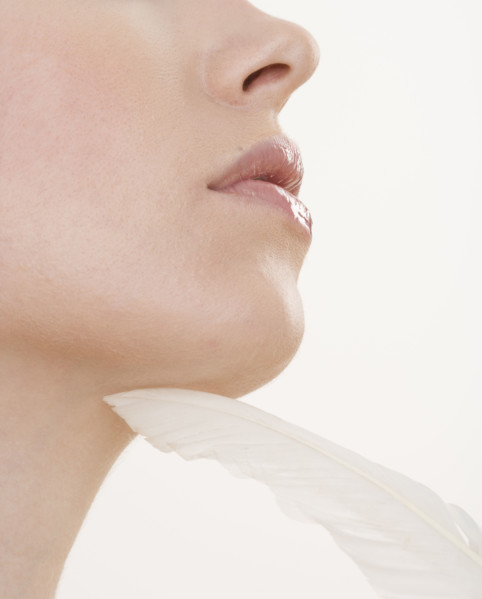 Feather touching woman’s chin.
