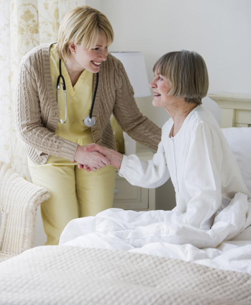 Nurse helping senior woman out of bed.