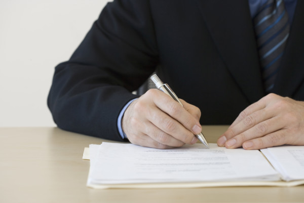 Businessman writing in folder.