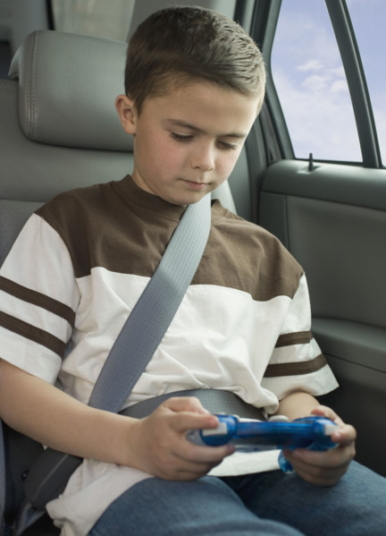 Boy playing video game in car.