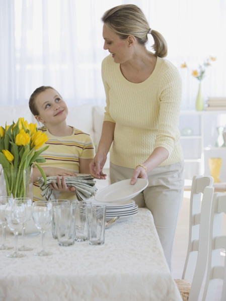 Mother and daughter setting table.