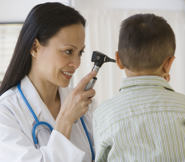 Asian female doctor examining boy’s ear.
