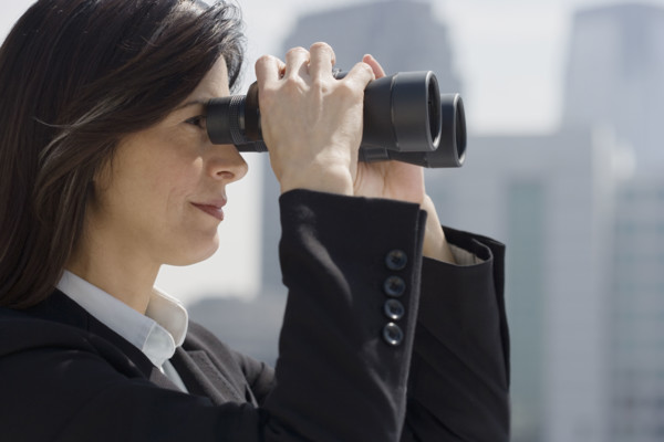 Businesswoman looking through binoculars.