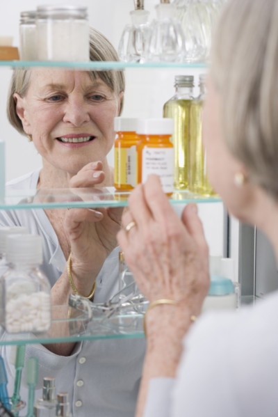 Senior woman looking in medicine cabinet.