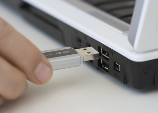 Man plugging USB stick into laptop.