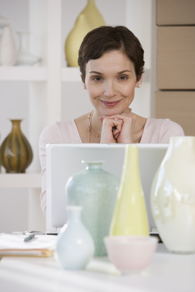 Woman with laptop in pottery store.