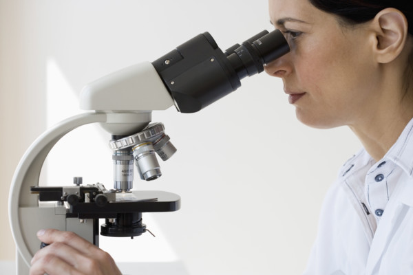 Female scientist looking into microscope.
