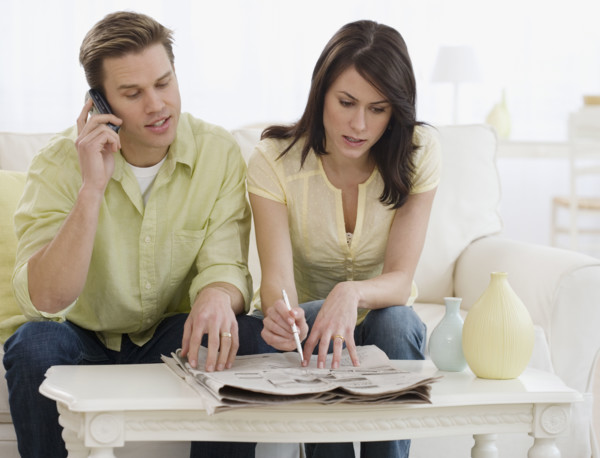 Couple reading classifieds in newspaper.