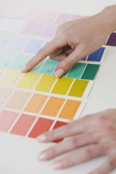 Close up of woman comparing paint swatches.
