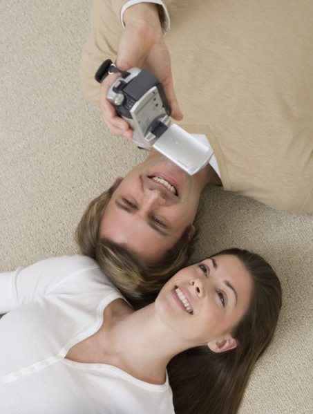 Couple video recording themselves on floor.
