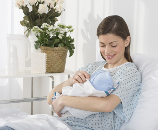 Mother smiling at newborn baby in hospital.