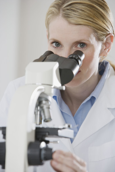Female scientist looking into microscope.