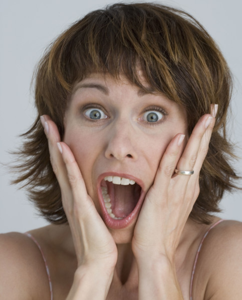 Woman looking surprised with hands on cheeks.