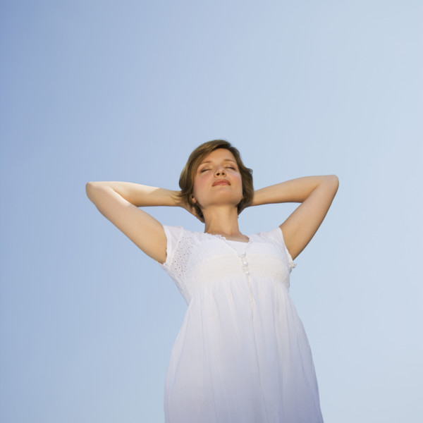 Low angle view of woman with arms behind head.