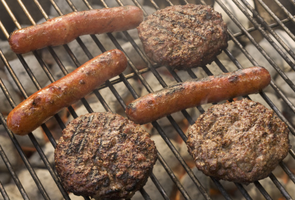 Hot dogs and hamburgers cooking on grill.
