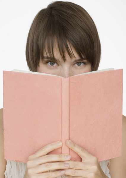 Woman holding open book over face.