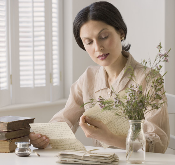 Woman in vintage clothing reading letter.