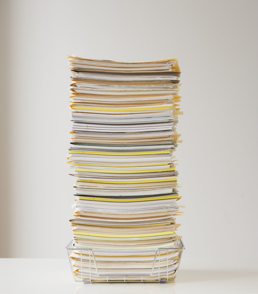 Large stack of paperwork in wire basket.
