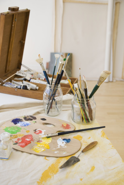 Artist’s palette and paintbrushes on table.