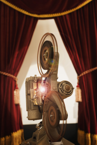 Old fashioned movie projector in between stage curtains.