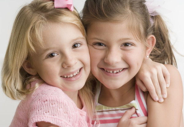 Two young sisters hugging and smiling. Date : 2006