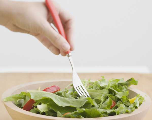 Woman sticking fork in salad. Date : 2006