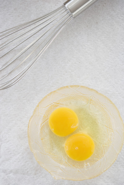 High angle view of whisk next to eggs in bowl. Date : 2006