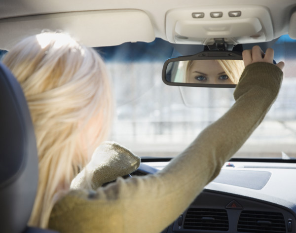 Woman adjusting car rear view mirror. Date : 2007