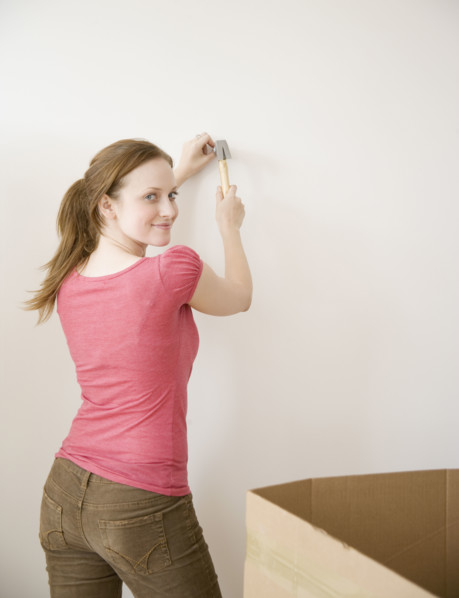 Woman hammering nail in wall. Date : 2006
