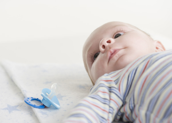 Close up of baby lying down next to pacifier. Date : 2006