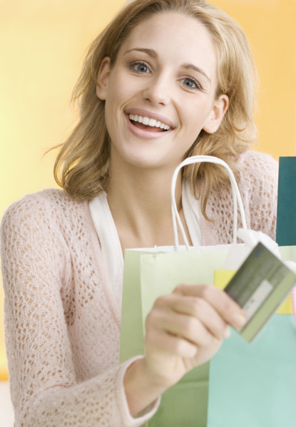 Woman with shopping bags holding credit card   . Date : 2006