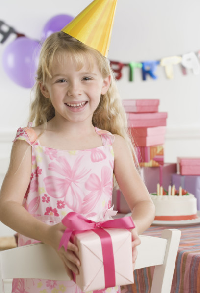 Young girl wearing party hat and holding gift. Date : 2006