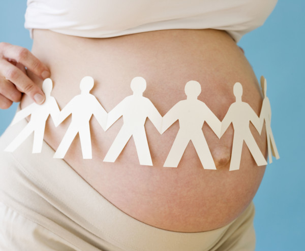 Pregnant woman holding paper dolls around belly. Date : 2007